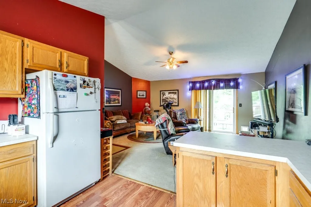 Kitchen featuring freestanding refrigerator, open floor plan, light wood-style flooring, light countertops, and a ceiling fan
