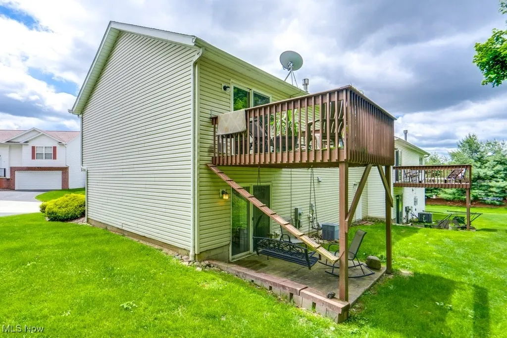 View of home's exterior with a deck, a yard, and cooling unit