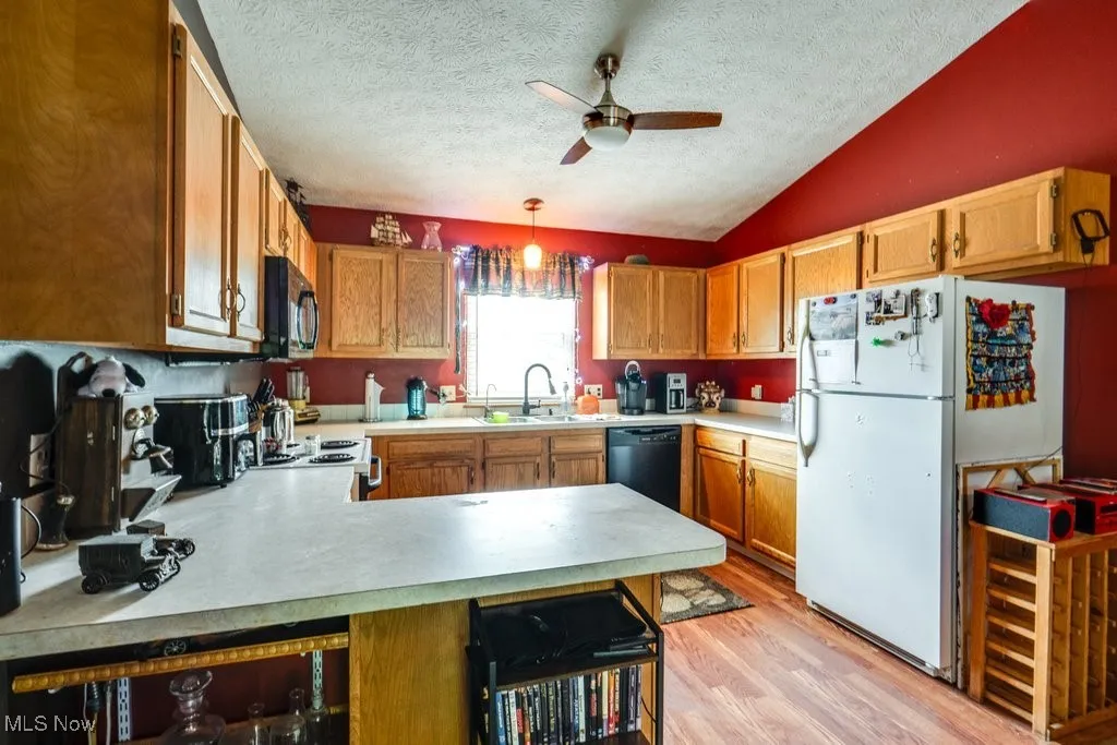 Kitchen featuring ceiling fan, white appliances, a sink, light wood finished floors, and light countertops