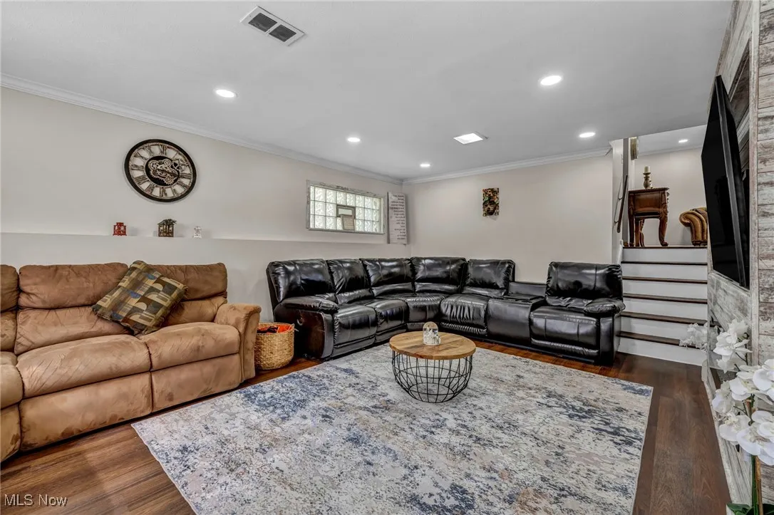 Living area with ornamental molding, wood finished floors, and recessed lighting