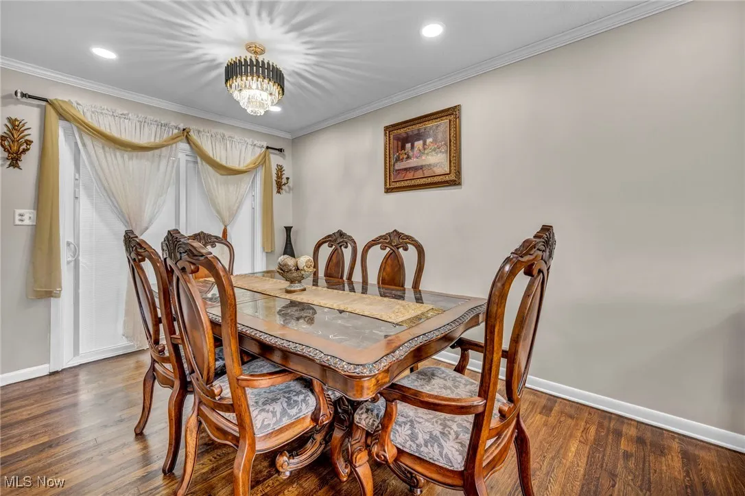 Dining area featuring baseboards, a chandelier, wood finished floors, crown molding, and recessed lighting