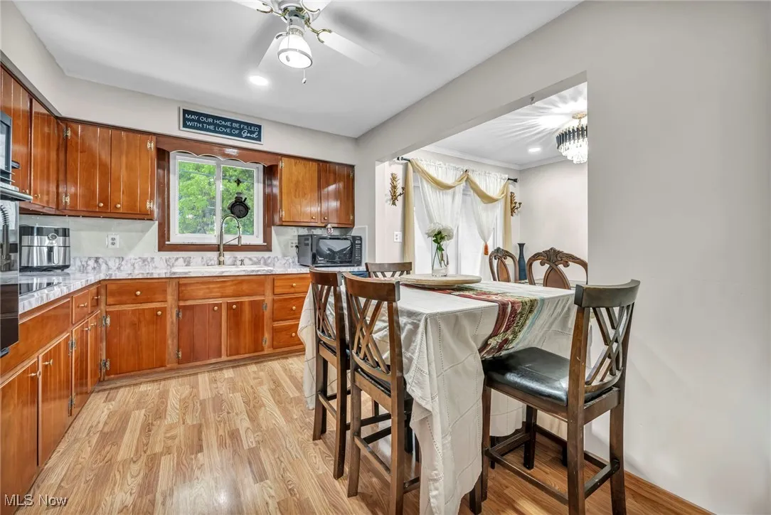 Kitchen featuring black microwave, a sink, brown cabinetry, light countertops, and recessed lighting
