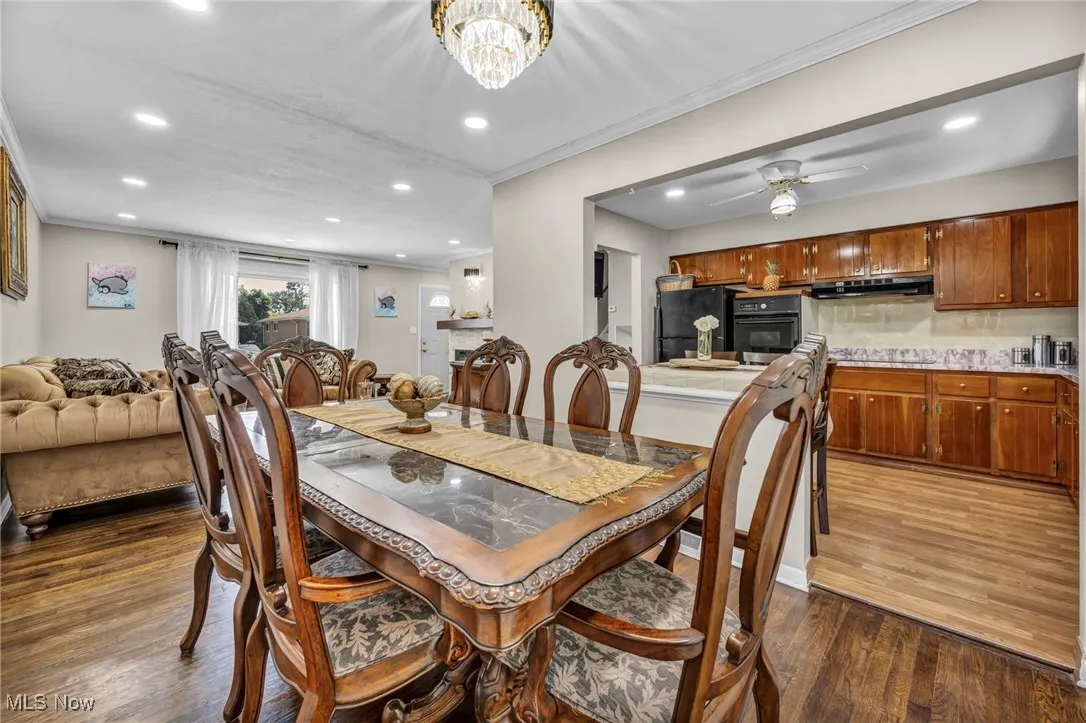 Dining space with crown molding, recessed lighting, dark wood-style flooring, a chandelier, and ceiling fan