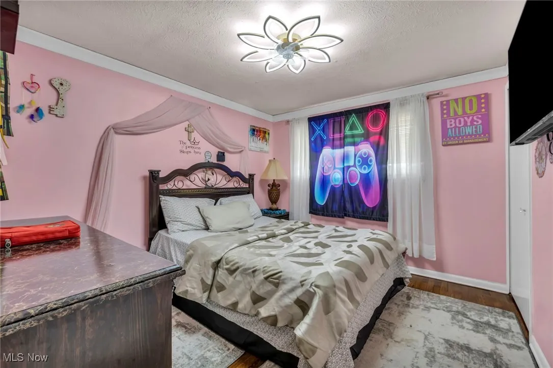 Bedroom featuring wood finished floors, a textured ceiling, and baseboards