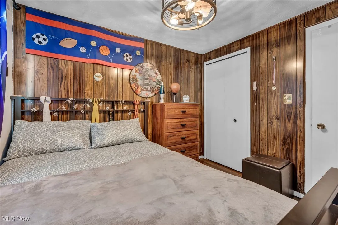 Bedroom featuring a chandelier, wood walls, and a closet