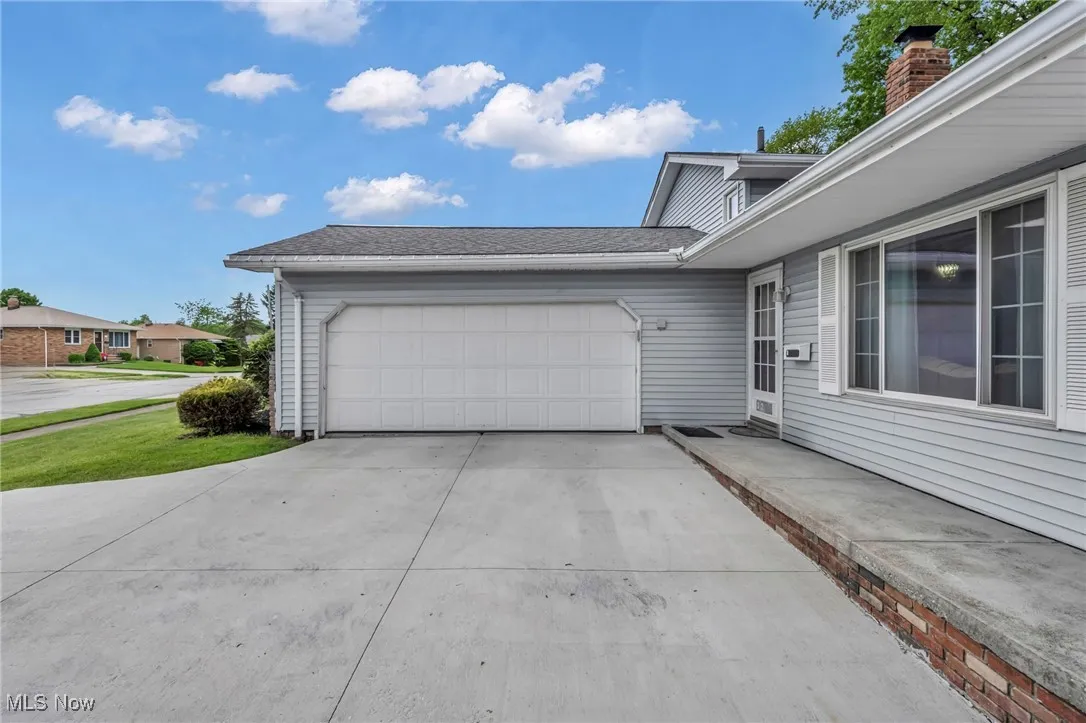 View of property exterior featuring an attached garage and concrete driveway