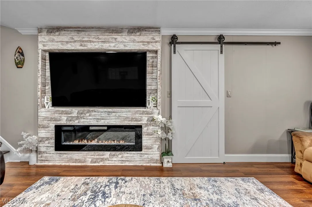 Detailed view of a fireplace, wood finished floors, baseboards, and crown molding