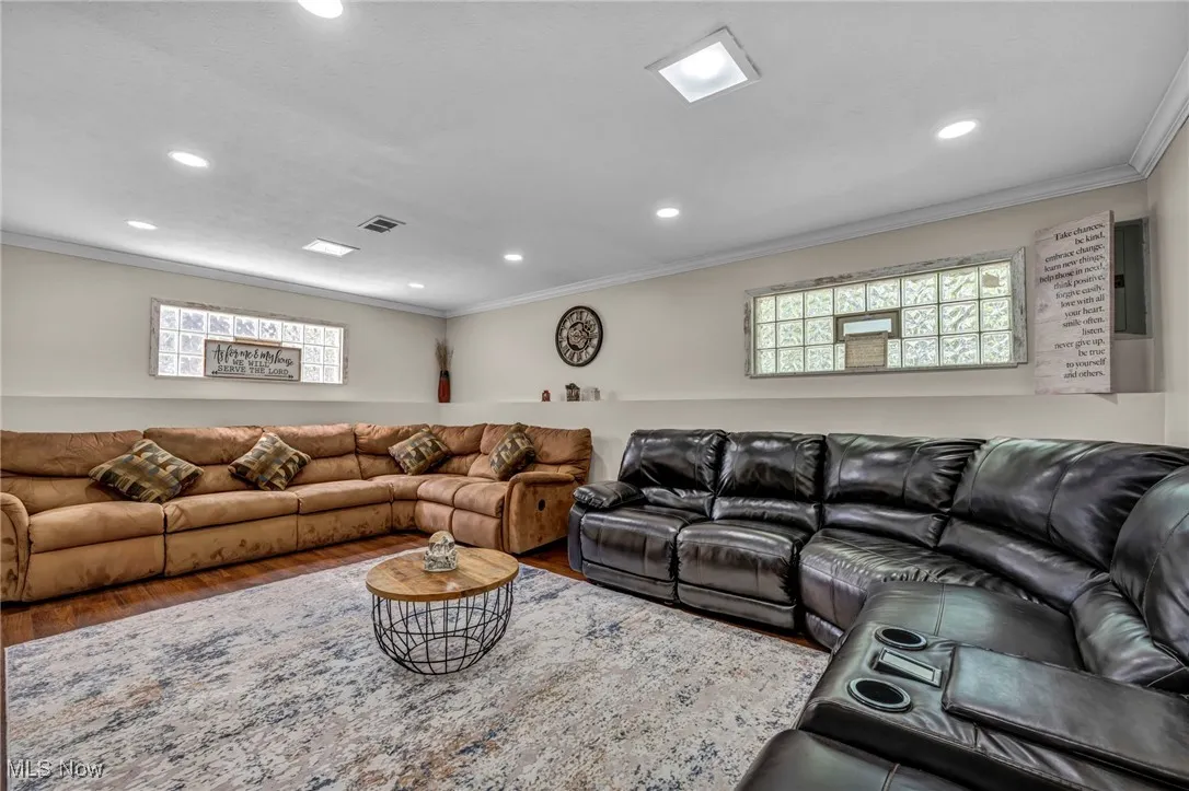 Living room with wood finished floors, recessed lighting, electric panel, crown molding, and healthy amount of natural light