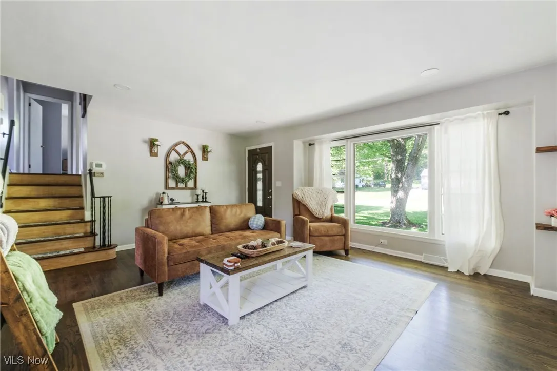 Living area featuring wood finished floors, stairway, and baseboards