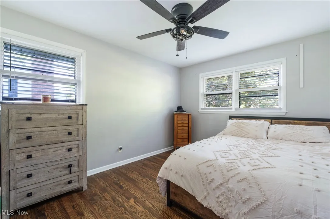 Bedroom featuring dark wood-style floors, baseboards, and ceiling fan