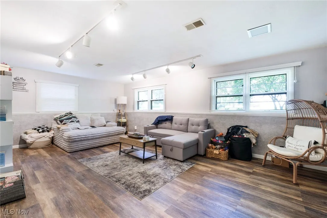Living area featuring rail lighting, wood finished floors, and wainscoting