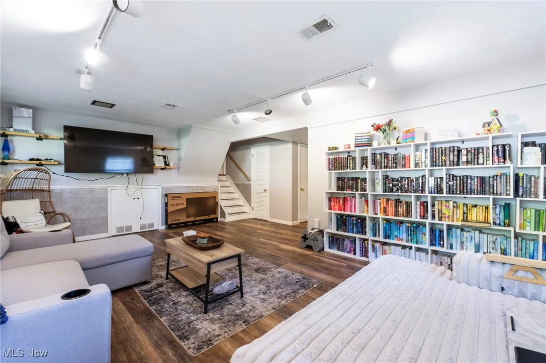 Living area with track lighting, wood finished floors, and stairs