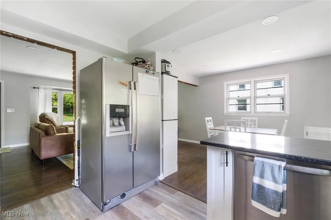 Kitchen featuring stainless steel appliances, light wood-style floors, baseboards, recessed lighting, and dark stone countertops