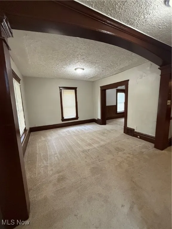 Empty room featuring carpet, baseboards, and a textured ceiling
