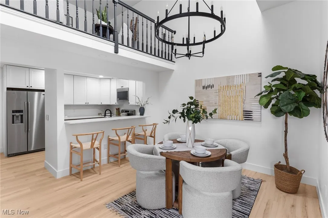 Dining room with light wood-type flooring, a towering ceiling, baseboards, and a chandelier