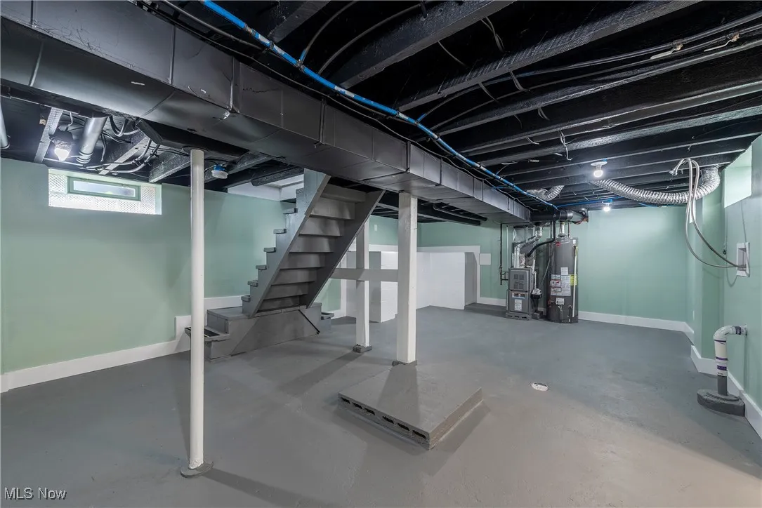 Basement featuring water heater, baseboards, and stairs