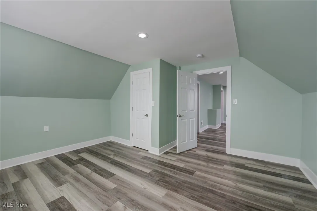 Additional living space featuring lofted ceiling, baseboards, wood finished floors, and recessed lighting