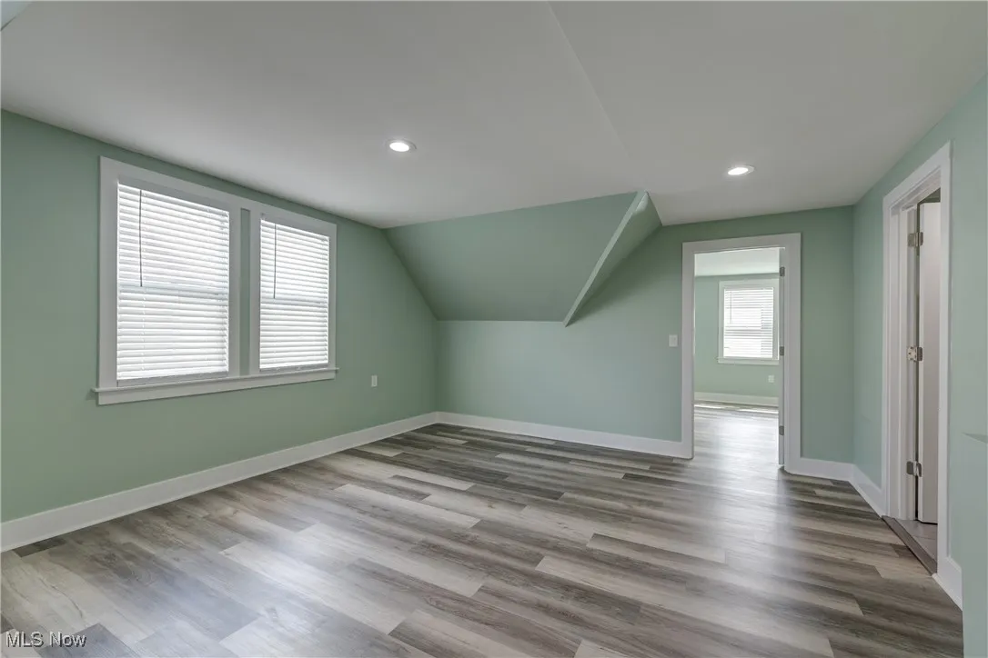 Additional living space with baseboards, recessed lighting, wood finished floors, and vaulted ceiling