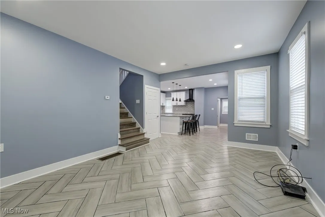 Unfurnished living room with baseboards, stairs, and recessed lighting