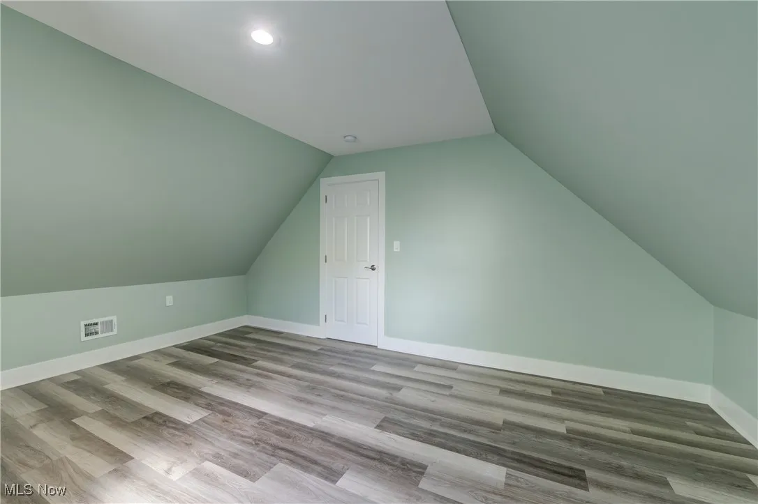 Additional living space featuring vaulted ceiling, baseboards, wood finished floors, and recessed​​‌​​​​‌​​‌‌​‌‌​​​‌‌​‌​‌​‌​​​‌​​ lighting