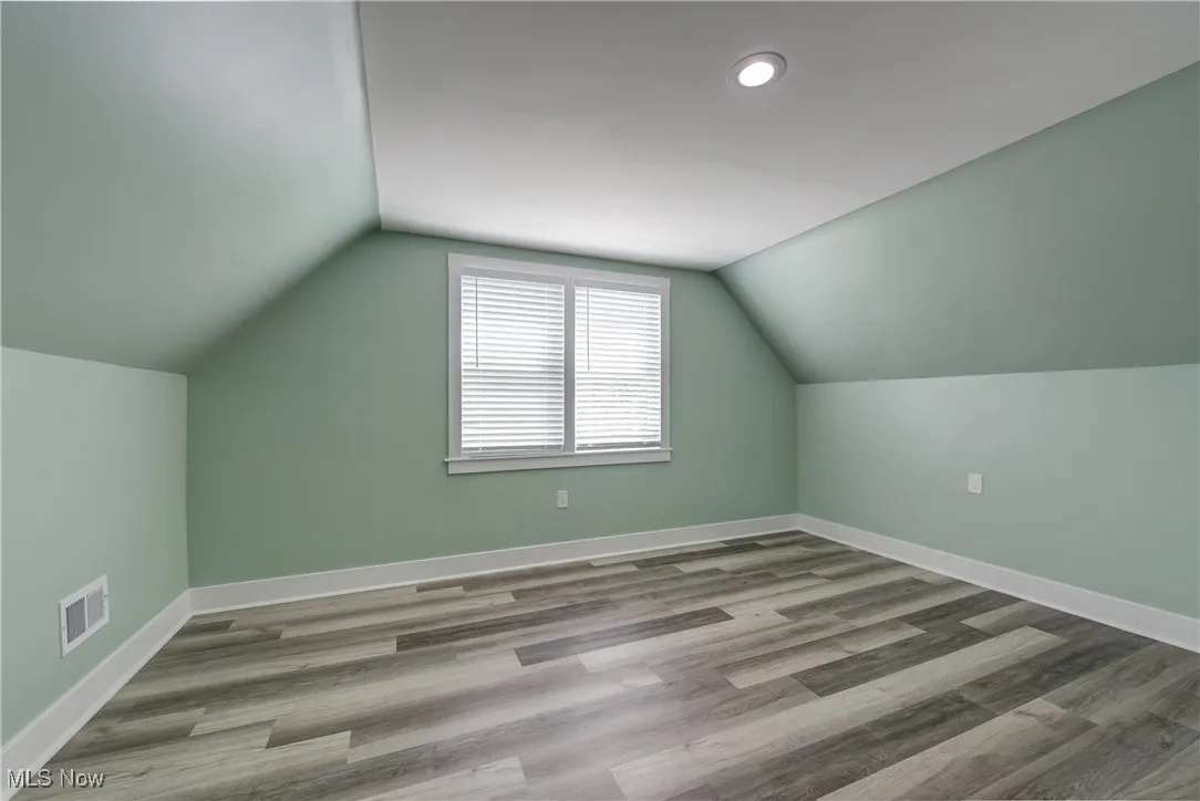 Additional living space with vaulted ceiling, wood finished floors, baseboards, and recessed lighting