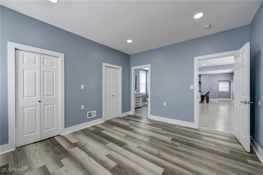 Unfurnished bedroom with multiple closets, wood finished floors, baseboards, and recessed lighting