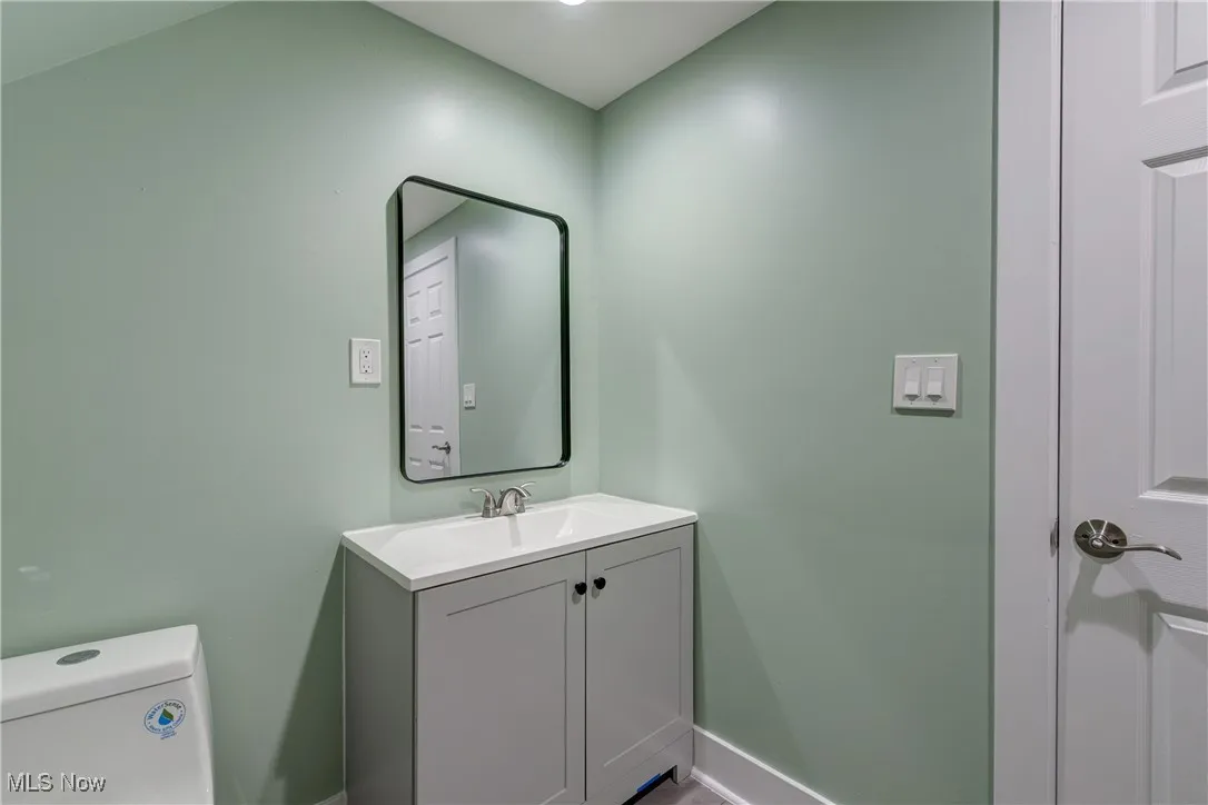 Half bathroom featuring baseboards, vanity, and toilet
