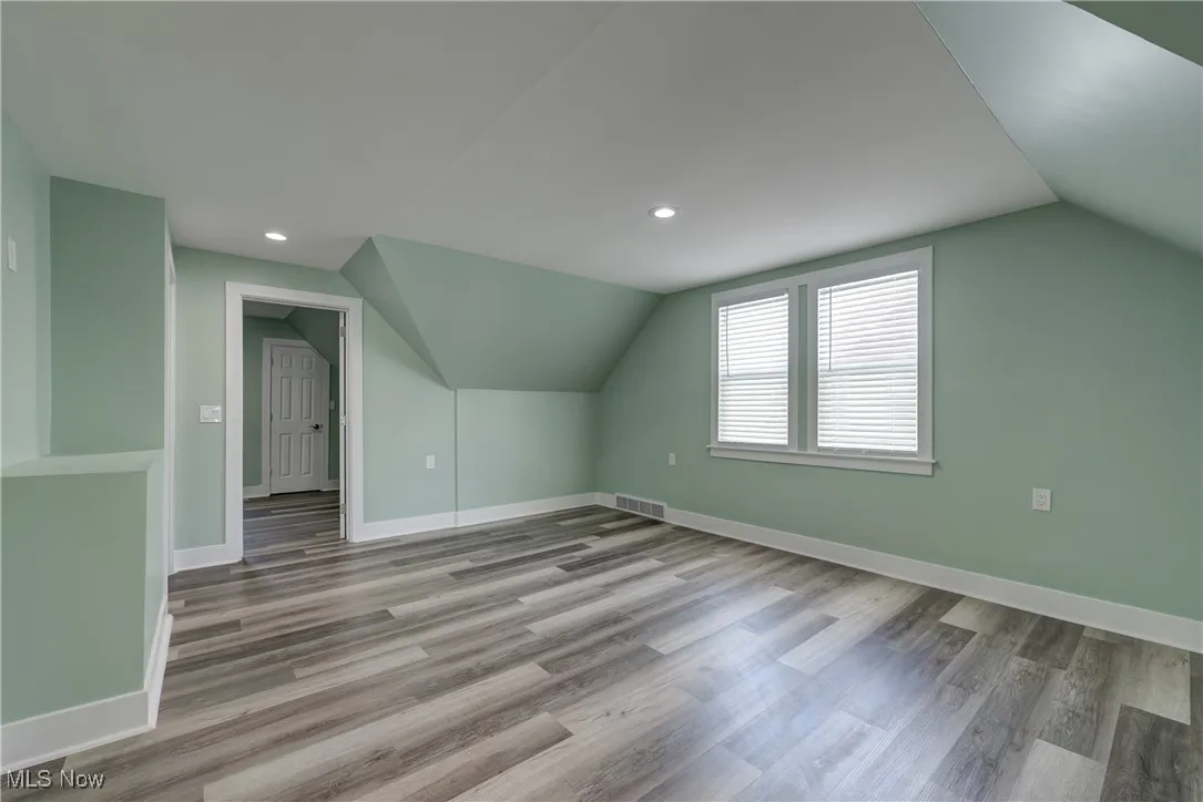 Additional living space with vaulted ceiling, baseboards, wood finished floors, and recessed lighting