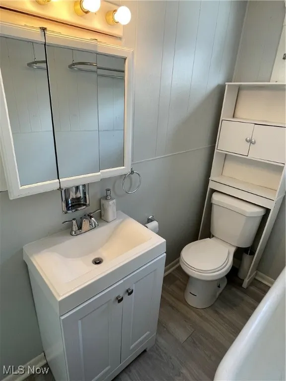 Bathroom with toilet, vanity, and wood finished floors