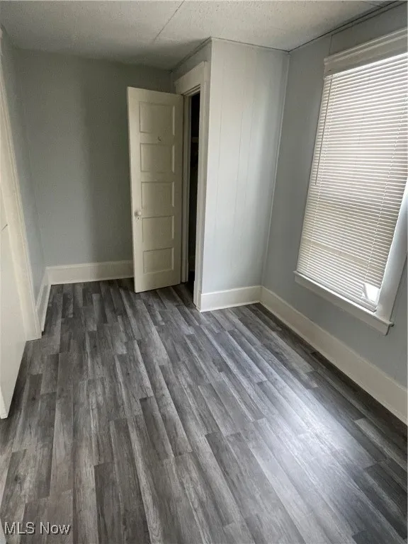 Spare room with dark wood-style flooring and baseboards