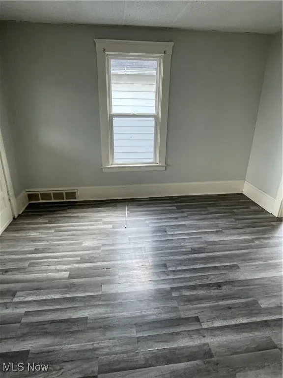 Spare room with baseboards and wood finished floors