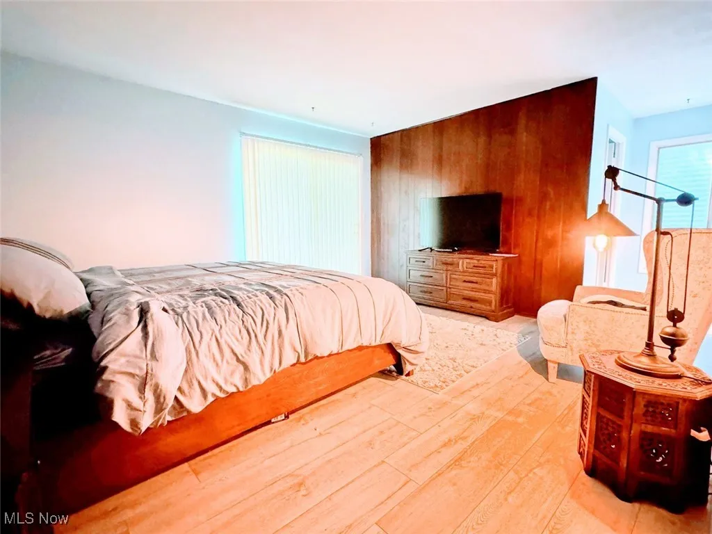 Bedroom featuring light wood-type flooring and wooden walls