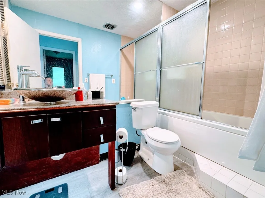 Full bathroom featuring vanity, enclosed tub / shower combo, toilet, and tile patterned floors