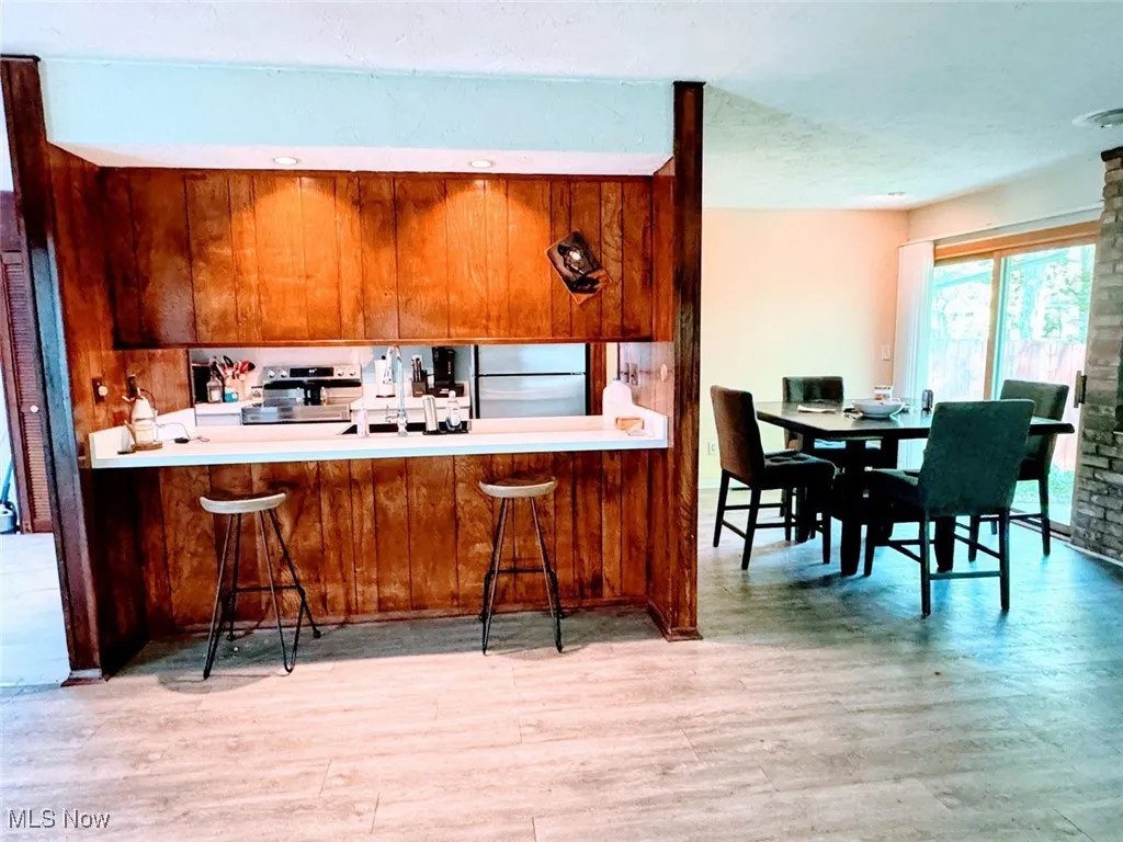 Kitchen with fridge, brown cabinets, a breakfast bar area, and wood finished floors