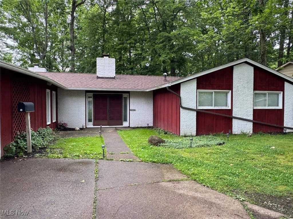 View of front of house featuring a chimney, brick siding, a front lawn, and a shingled roof
