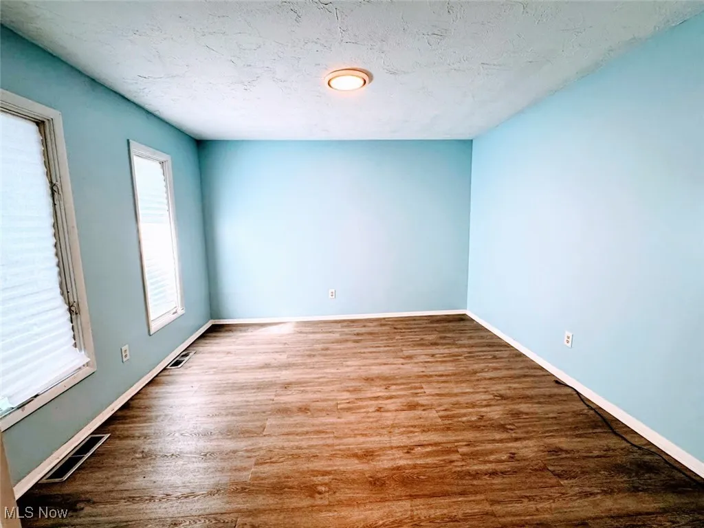 Unfurnished room with wood finished floors and baseboards