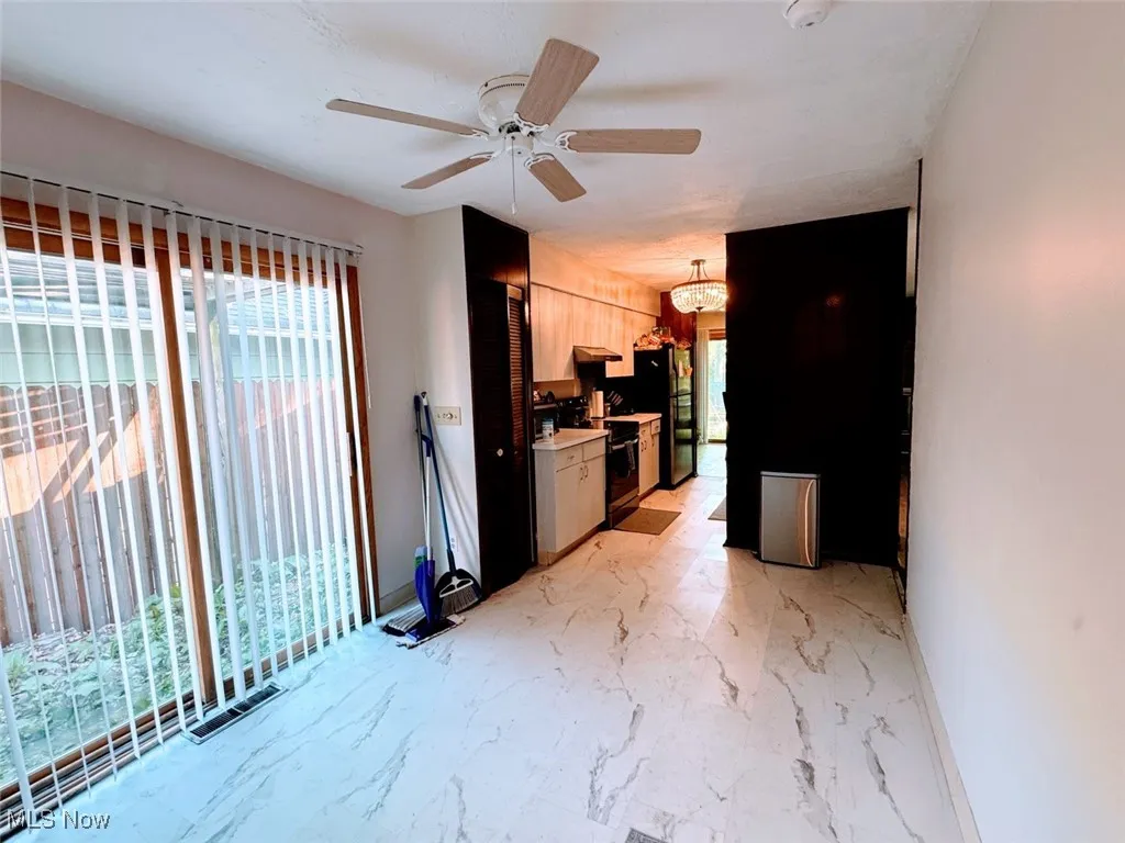 Kitchen featuring black appliances, a ceiling fan, light countertops, light marble finish floors, and a chandelier