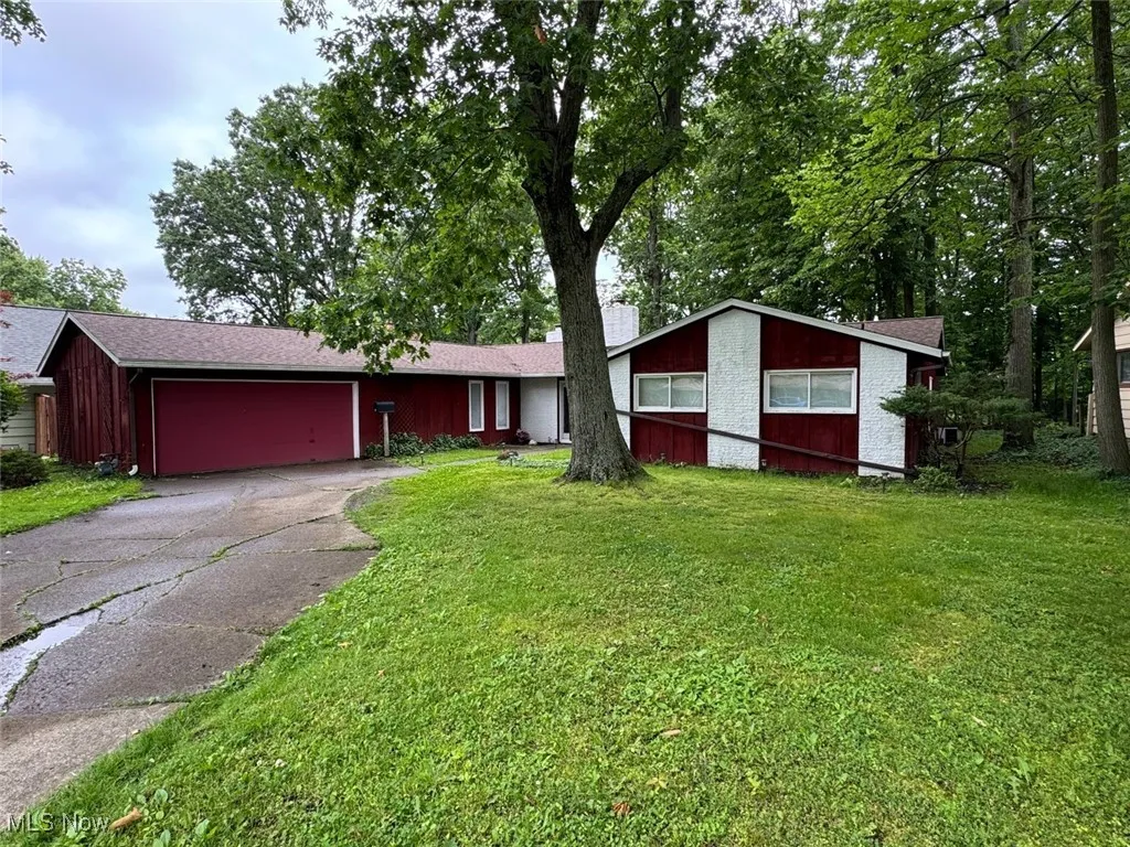 View of front of home featuring asphalt driveway, an attached garage, a front yard, and a chimney