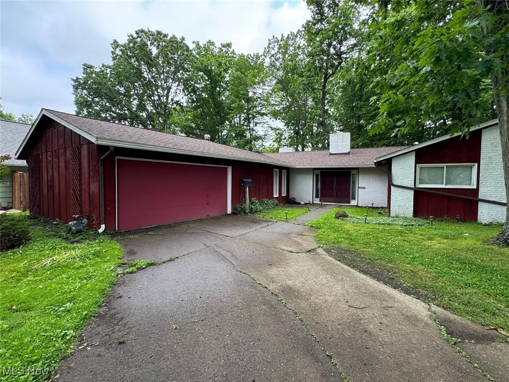 View of front facade with a chimney, a front yard, a garage, driveway, and brick siding