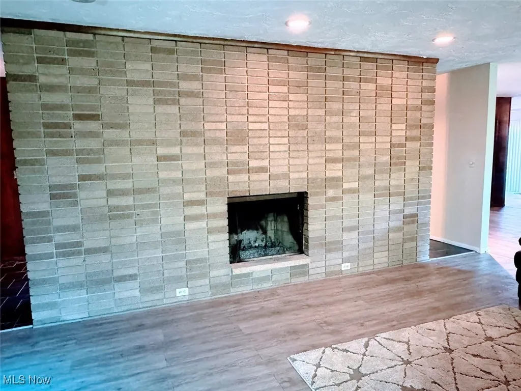 Detailed view of a brick fireplace, wood finished floors, and recessed lighting
