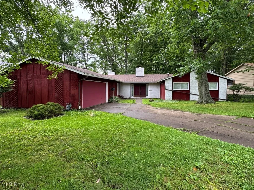 Mid-century modern home featuring a front yard, an attached garage, asphalt driveway, and a chimney