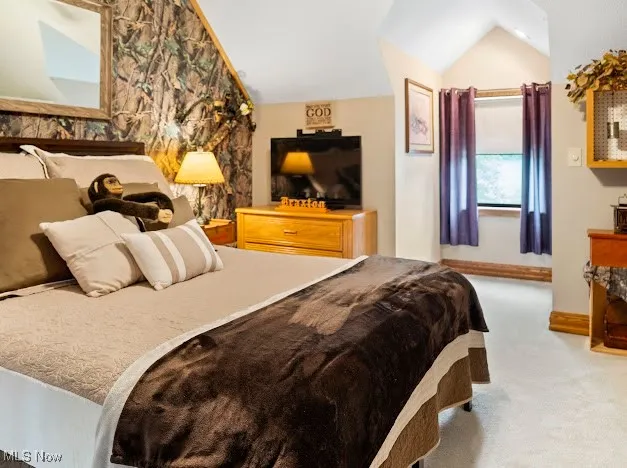 Bedroom featuring lofted ceiling, carpet flooring, and baseboards