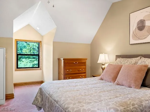 Bedroom with vaulted ceiling, carpet floors, and baseboards