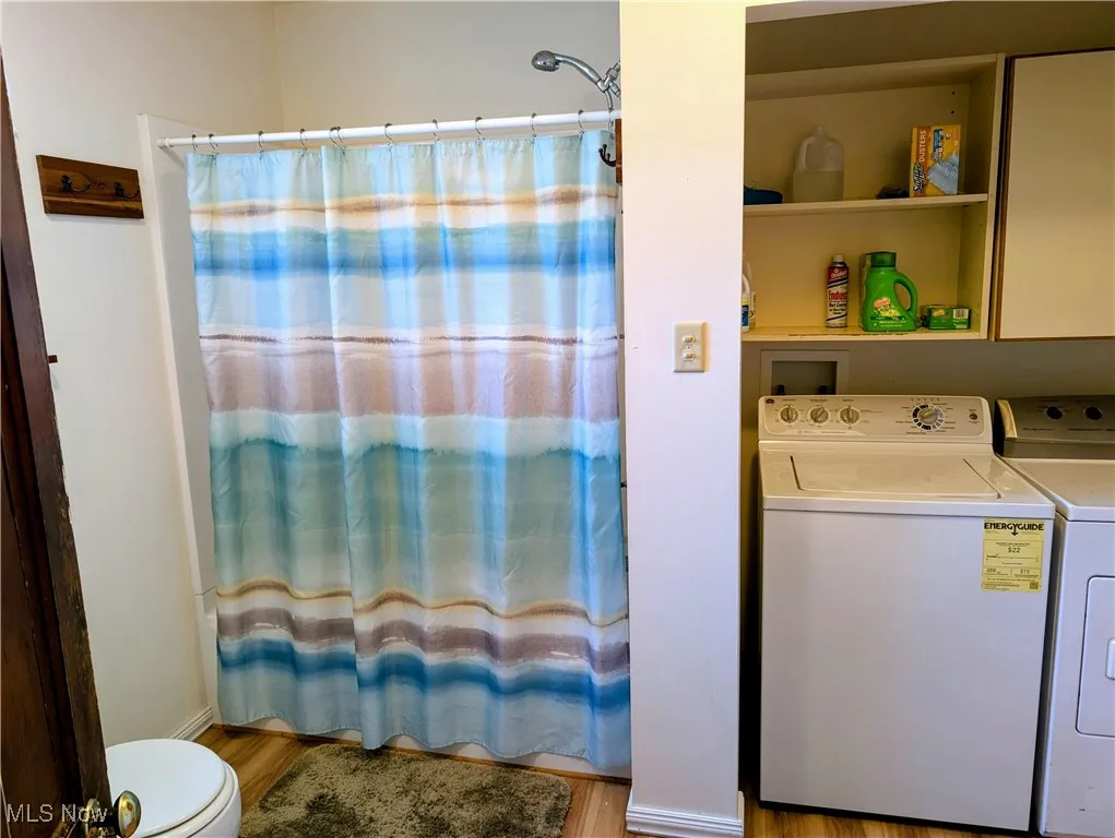 Washroom featuring washing machine and dryer and wood finished floors