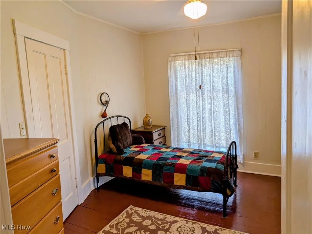 Bedroom with wood finished floors and ornamental molding