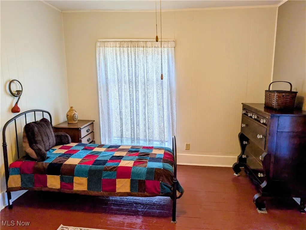 Bedroom featuring wood finished floors, baseboards, and crown molding