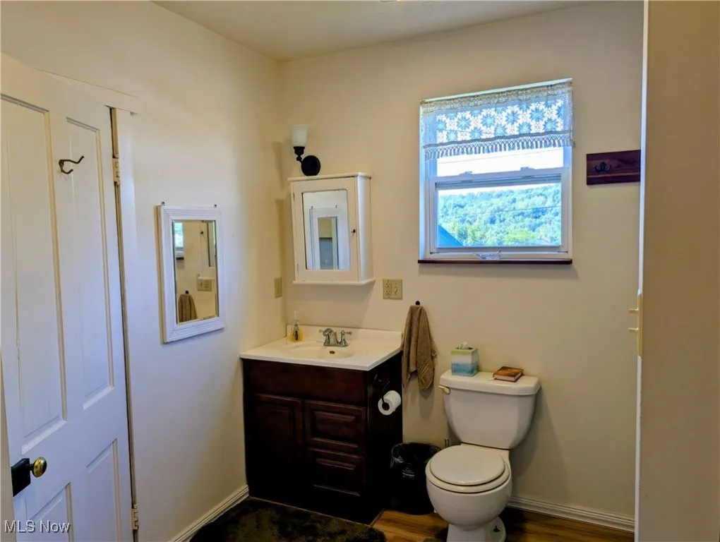 Bathroom with toilet, vanity, and baseboards