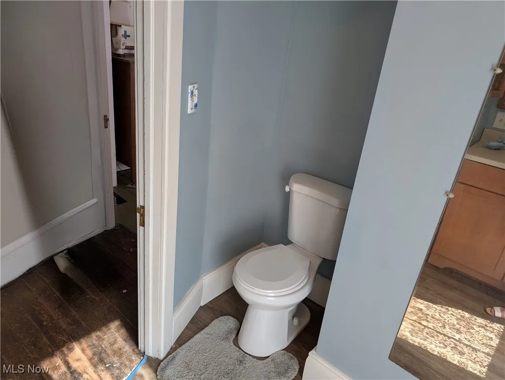 Bathroom featuring wood finished floors, baseboards, and toilet