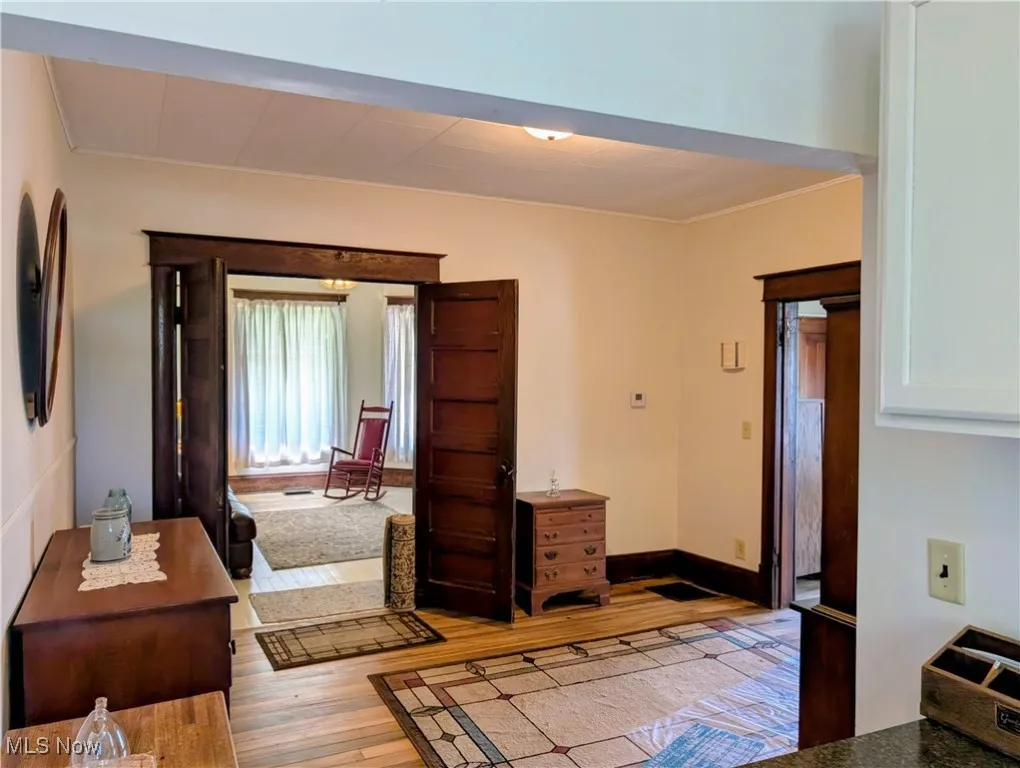 Entryway with light wood finished floors, crown molding, and baseboards