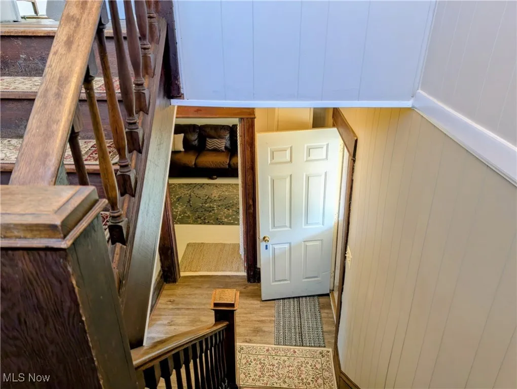 Stairway with wood finished floors and a decorative wall